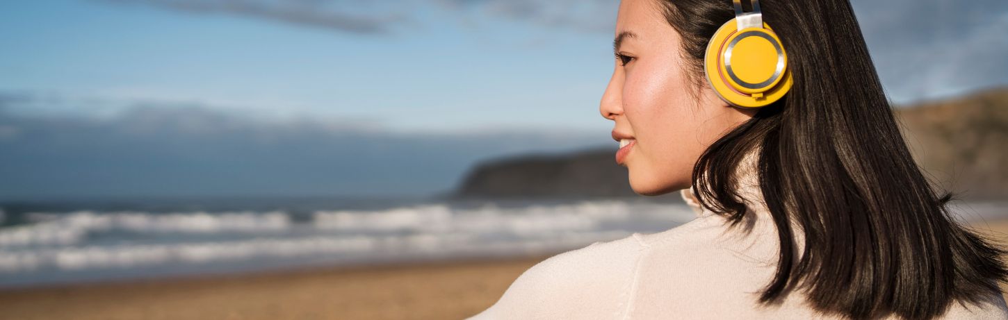 Femme écoutant de la musique face à la mer dans un cadre apaisant, illustrant l’article de blog « La méthode Tomatis et l’intuition » de Sylvie Petitjean.
